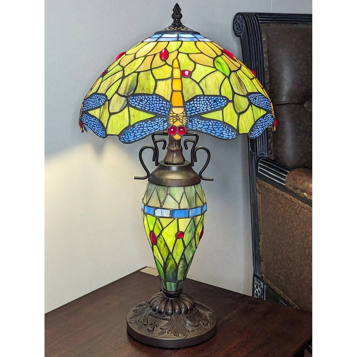 Stained glass lamp with dragonfly design on a wooden surface.