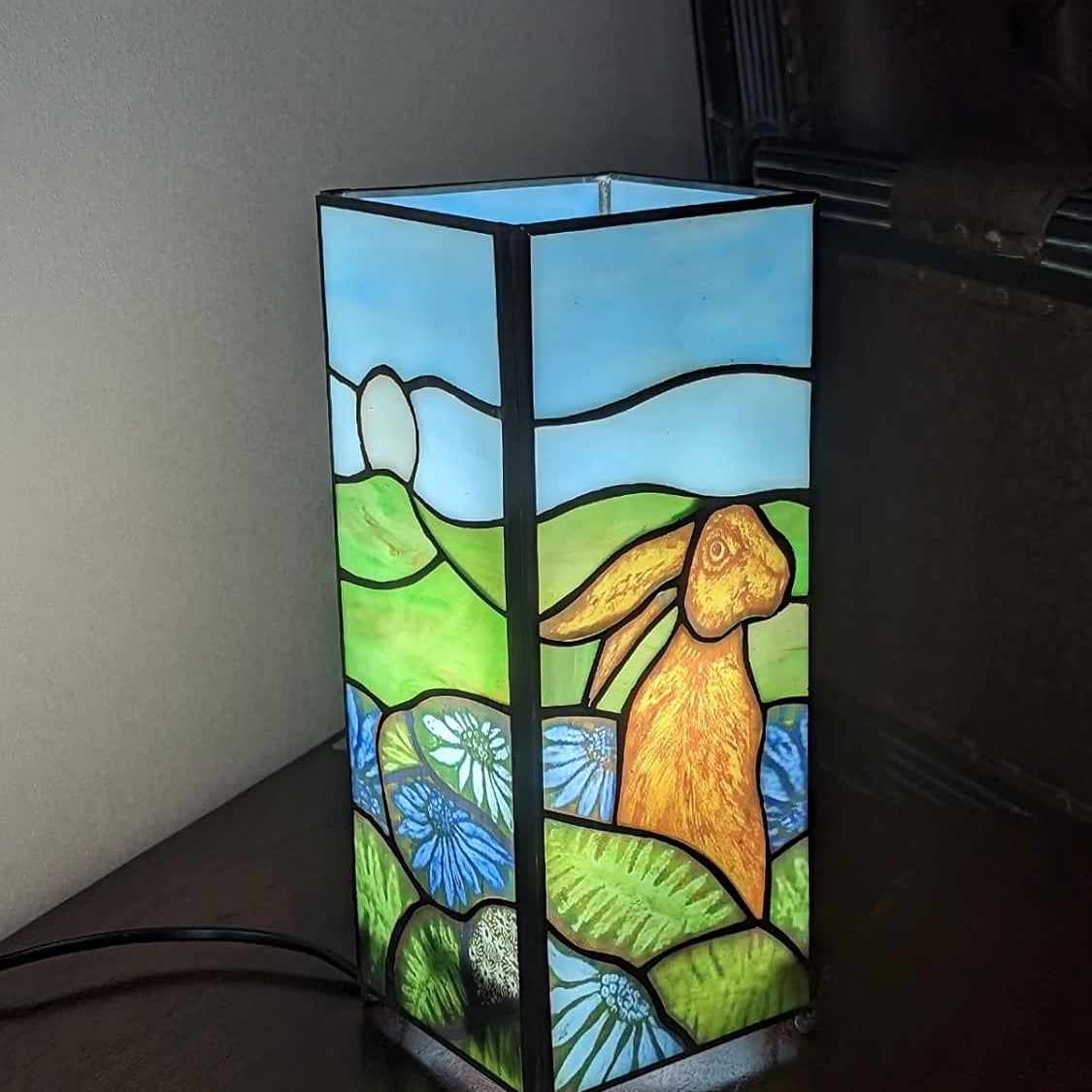 Rabbit design square Tiffany table lamp illuminated with stained glass depicting a hare in a field | stained glass