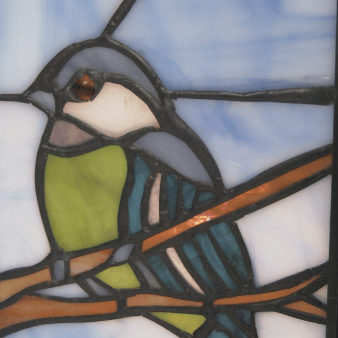 Close-up of blue tit stained glass panel on square Tiffany table lamp