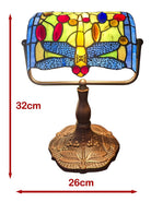 A stained glass desk lamp with a dragonfly design, featuring a bronze-colored metal base and a colorful glass shade. Red dimension lines indicate a height of 32cm and a width of 26cm on a plain white background.