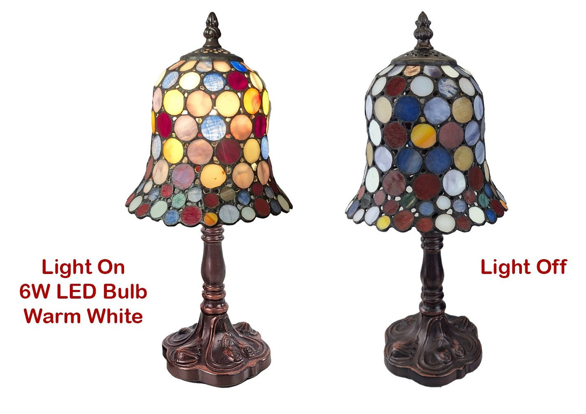 A stained glass table lamp shown in two states: light on with a multicolor glass shade and warm white glow, and light off with a darker glass shade. Both have dark bronze carved bases.
