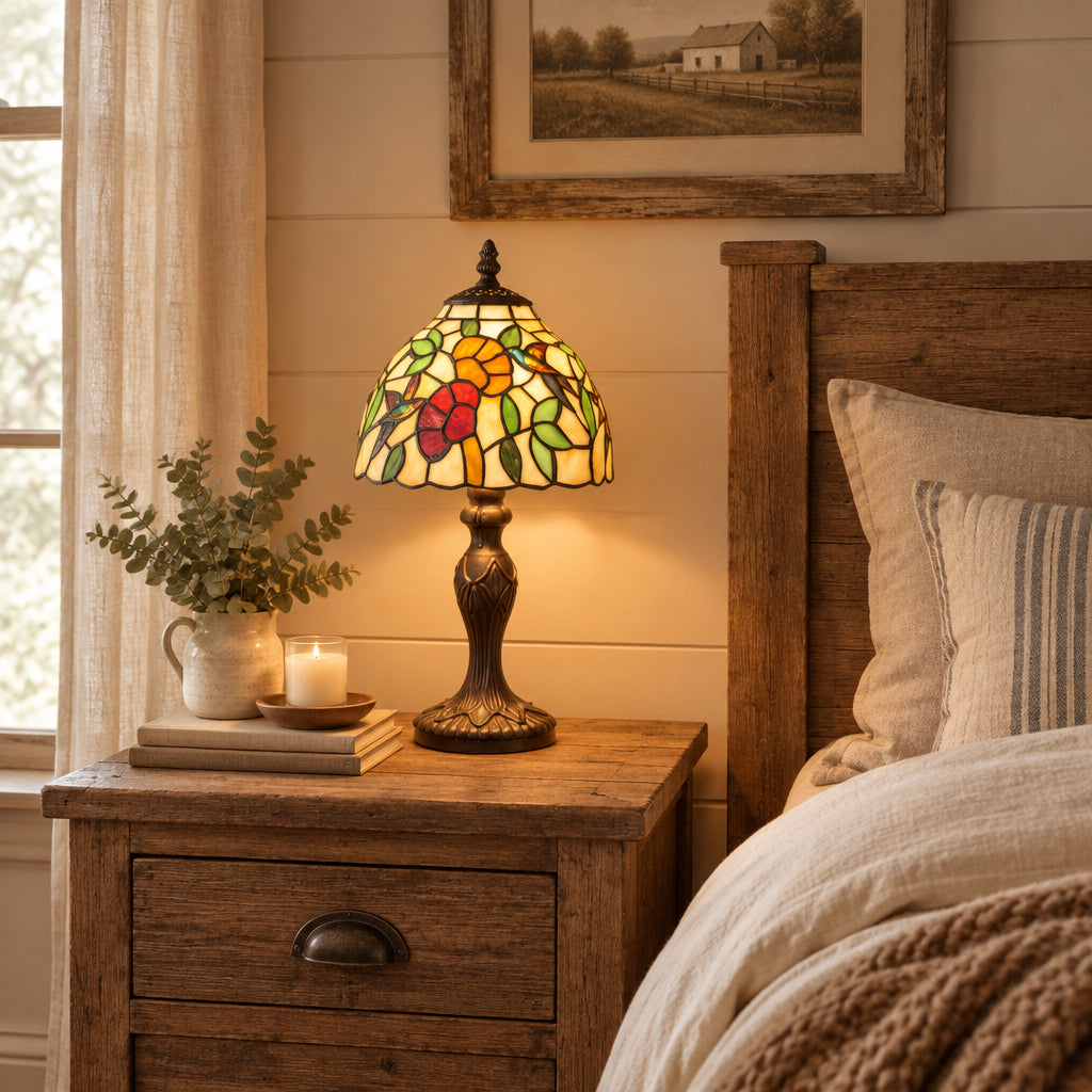 A Tiffany-style stained glass table lamp with a floral design in yellow, green, red, and orange, set on a dark wooden table next to a dark leather chair.