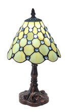 A Tiffany style table lamp with a cream-coloured glass shade decorated with blue jewels, mounted on a dark base.