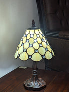 Decorative table lamp with stained glass shade on a wooden surface.