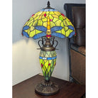 Stained glass lamp with dragonfly design on a wooden surface.