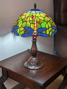 Stained glass lamp with dragonfly design on a wooden table