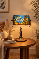 Decorative Tiffany style table lamp with stained glass shade on a wooden table.
