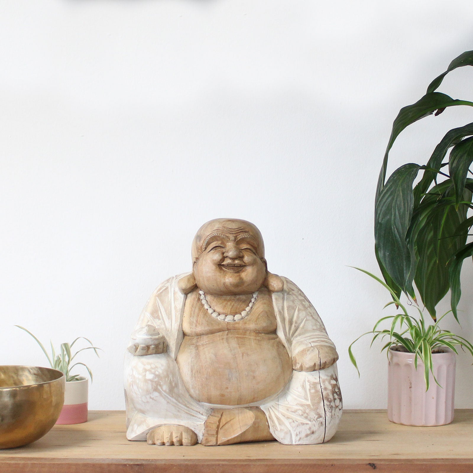 Buddha statue on a wooden surface with plants in the background