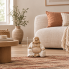 A small seated Buddha figurine in a warm beige stone-like finish is placed on a patterned rug in a styled living room. A vertical arrow with '30 cm' text indicates the figurine's height.